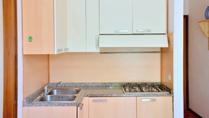 A kitchen with a granite countertop, stainless steel sink, and a gas stove. - Cozy Two-room Flat 100mt From Bibione Beach (San Michele al Tagliamento)