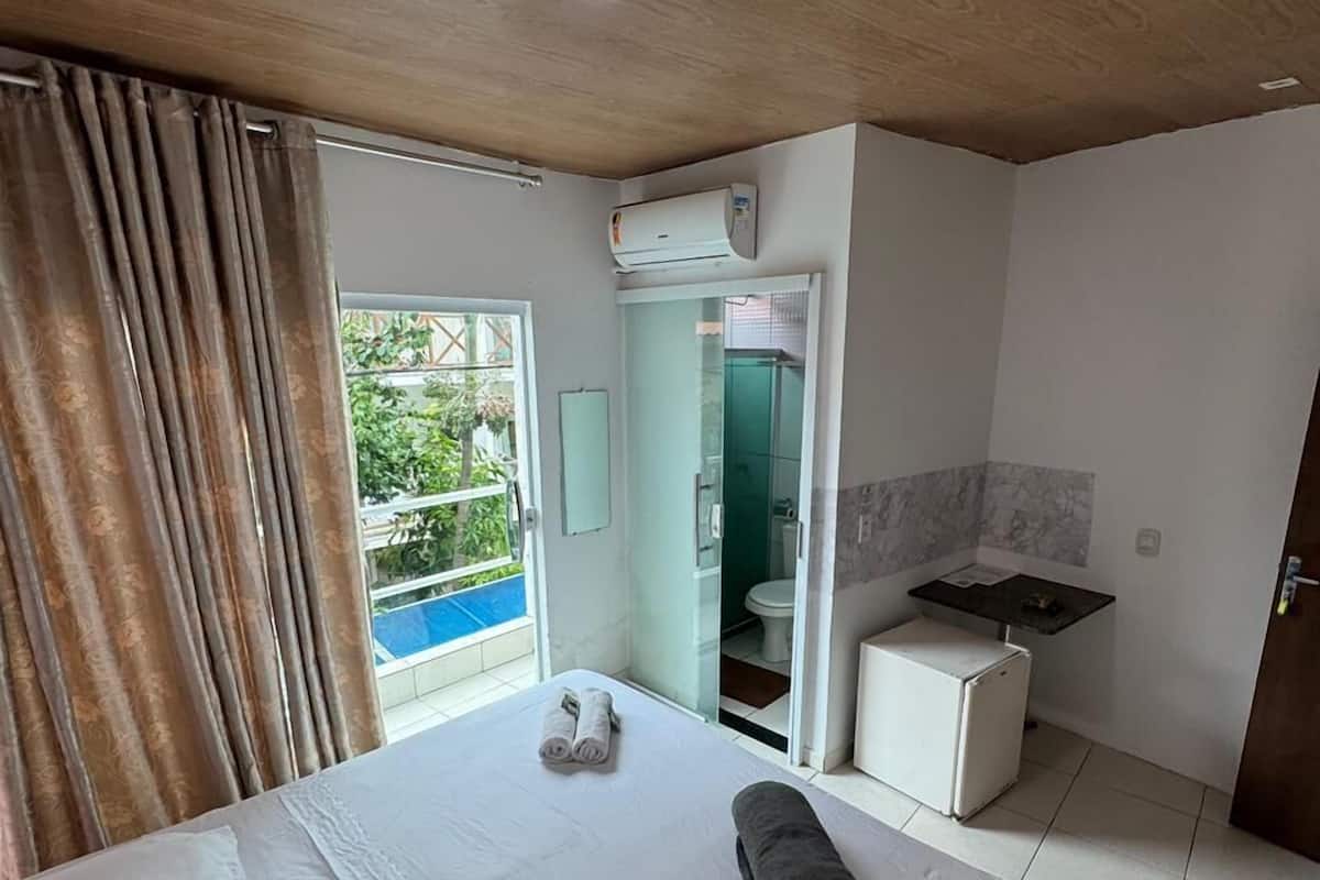 Una habitación de hotel con cama, kitchenette, baño y vistas al exterior.