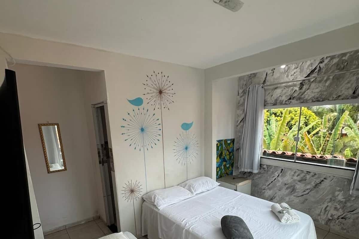 Un dormitorio con una cama, una cama individual, una ventana con vistas a la vegetación y una pared de mármol.
