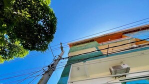 Un edifici de diverses plantes amb façana de rajola, un aparell d'aire condicionat visible i una finestra amb reixa de metall.