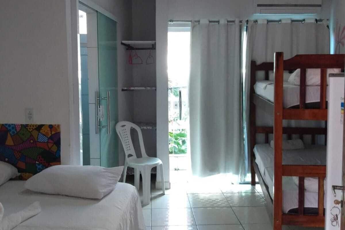 Un dormitorio con una cama, una litera, una silla y una obra de arte colorida en la pared.