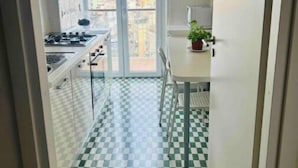 Una cocina estrecha con piso a cuadros, una estufa y un ventanal con vistas a la ciudad.
