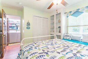 Une chambre à coucher avec un lit, une fenêtre avec des stores, un ventilateur de plafond et un placard avec une porte.