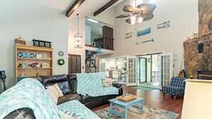A spacious living room with a leather sofa, a small table, and a bookshelf. There is a staircase leading to an upper level, and a stone wall on one side. - LakingitEz..3BR/2BA amazing sunsets & hot tub (Inman)