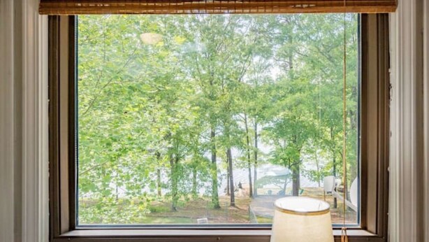 A window with a view of a forested area, a lamp on the windowsill, and a wooden blind. - LakingitEz..3BR/2BA amazing sunsets & hot tub (Inman)
