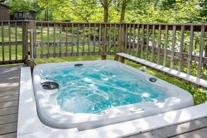 Un bain à remous sur une terrasse en bois, avec une clôture en bois en arrière-plan.