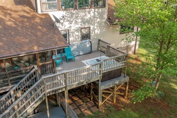 Une terrasse en bois avec un escalier menant à un deuxième niveau, une chaise bleue et une table de pique-nique.