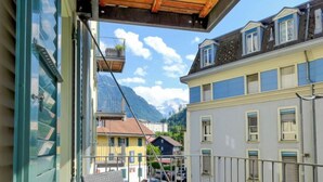 A balcony with a wooden ceiling overlooking a street with buildings and mountains in the background. - Apartment Orya by Interhome (Interlaken)
