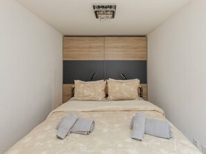 A bedroom with a bed, two pillows, a headboard, and a ceiling light fixture.
