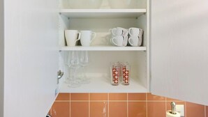 A kitchen with white shelves holding cups, glasses, and a roll of paper towels. - Apartment Orya by Interhome (Interlaken)
