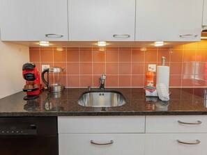 A kitchen with a stainless steel sink, a red coffee machine, and a glass carafe. - Apartment Orya by Interhome (Interlaken)
