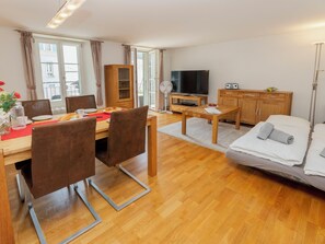 A modern living room with a dining area, a television, and a sofa. - Apartment Orya by Interhome (Interlaken)