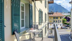 A balcony with a table and chairs, overlooking a street with buildings and mountains in the background. - Apartment Orya by Interhome (Interlaken)