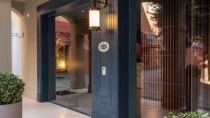 A hotel entrance with a dark facade, a glass door, and a visible interior through the glass. - Hotel Brun (Bologna)