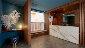 A reception area with a marble counter, wooden paneling, and a bench. - Hotel Brun (Bologna)