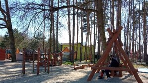 An outdoor play area with wooden structures and a sandy ground.