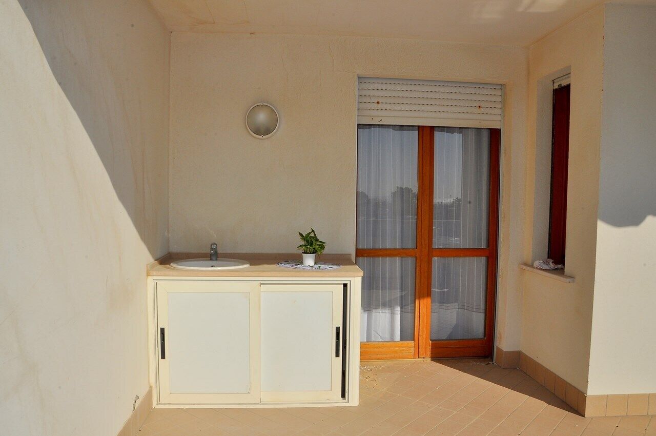 Une petite salle de bain avec un lavabo, un meuble et une fenêtre équipée de stores.