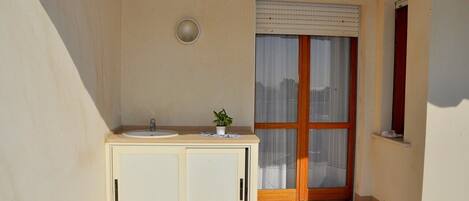 A small bathroom with a sink, cabinet, and a window with blinds.