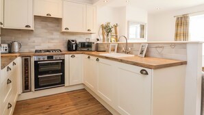 Una cocina moderna con armarios blancos, encimera de madera, horno empotrado, microondas y un lavamanos.
