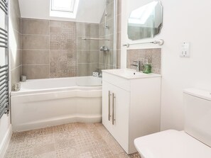 A modern bathroom with a freestanding bathtub, a glass shower enclosure, and a white vanity with a mirror.