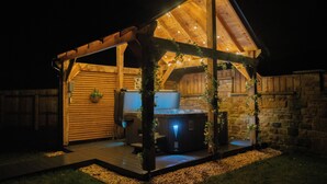 A wooden gazebo with a hot tub, surrounded by stone walls and a wooden fence. - Northumberland Luxury Stays - The Newland (Morpeth)