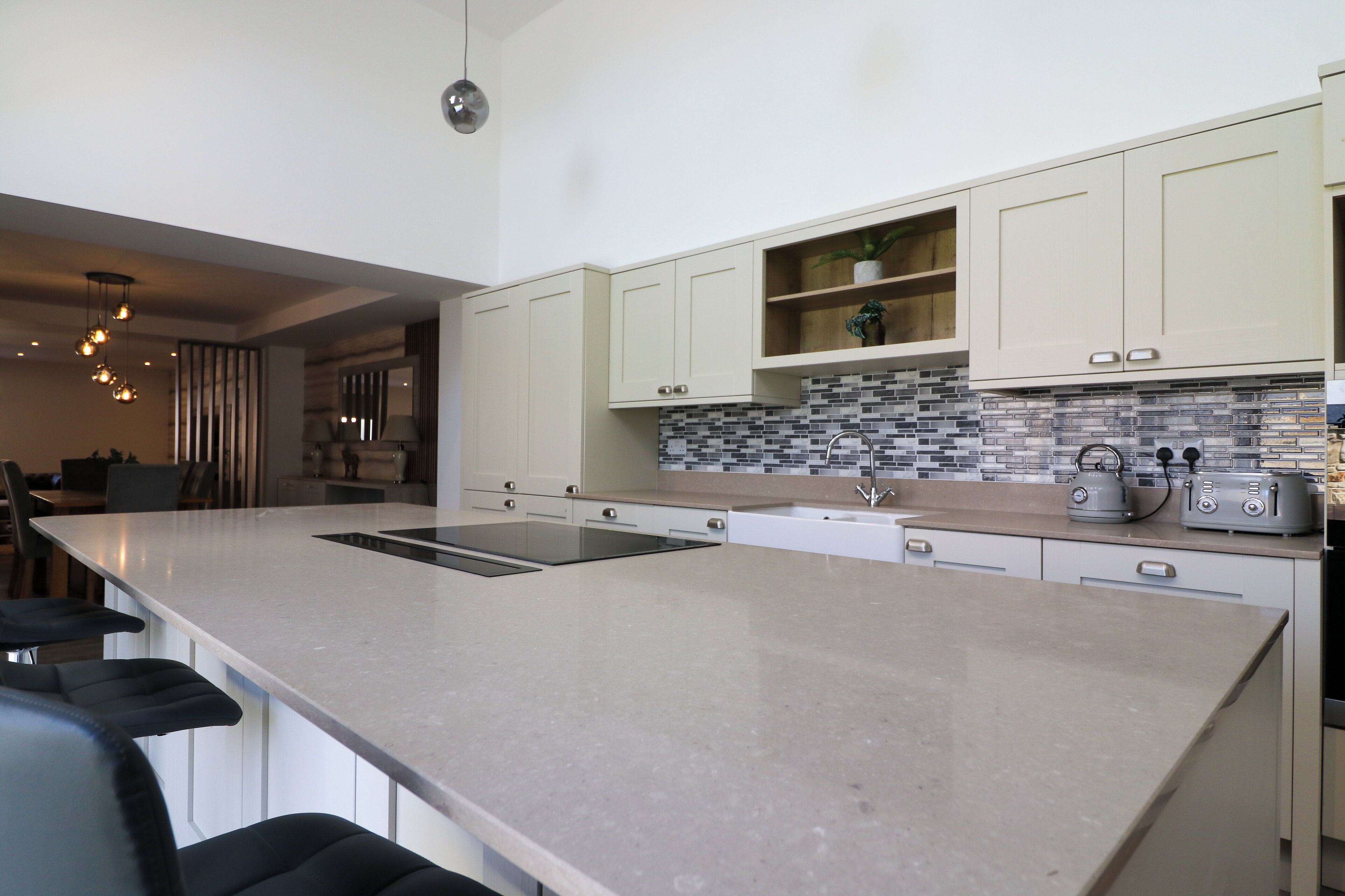 A modern kitchen with a large island, white cabinetry, and a tiled backsplash.