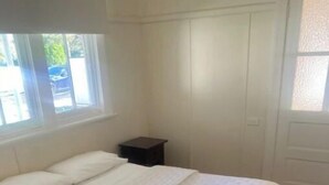 A bedroom with a bed, a nightstand, and a window. - Golden street cottage

 (West Wyalong)