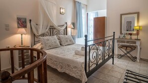 Quarto bem organizado com cama, abajures, mesa de cabeceira, cadeira de madeira e escrivaninha com espelho.
