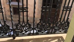 Un balcón con barandillas de metal negro ornamentado y suelo estampado.