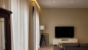 Un salón con un sofá, un televisor y una lámpara.