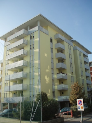 A multi-story building with balconies, a no parking sign, and a gated entrance.
