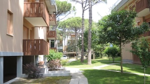A courtyard with a pathway, trees, and a building with balconies.
