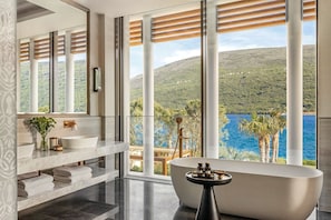 Une salle de bain moderne avec une baignoire sur pieds, un grand miroir et une vue sur un paysage montagneux.