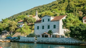 A stone building with a tiled roof, green shutters, and a small porch.