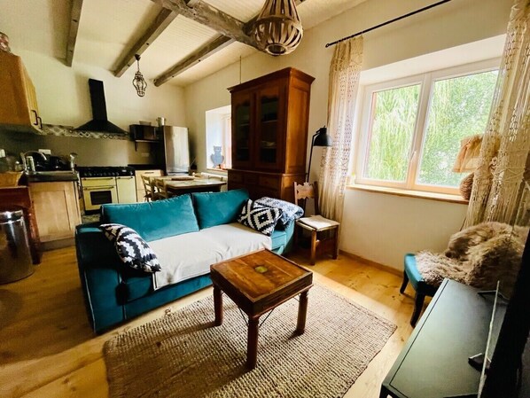 A cozy living room with a blue sofa, a wooden coffee table, and a view of the outdoors through a window.