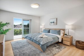 A bedroom with a bed, bedside tables, a lamp, a plant, and a view of the outside. - Spacious & Bright 3BR + 3BTH near UBC (direct road!) & Downtown (Vancouver)