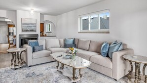 Una sala de estar moderna con un sofá color crema, una mesa de centro de vidrio y una chimenea.