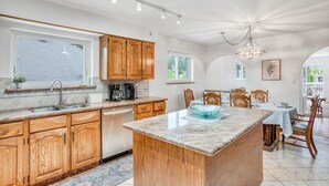 Una cocina moderna con armarios de madera, una isla central y una zona de comedor con mesa y sillas.