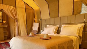 Quarto de hotel com uma cama grande, uma escada de madeira e um tapete estampado.
