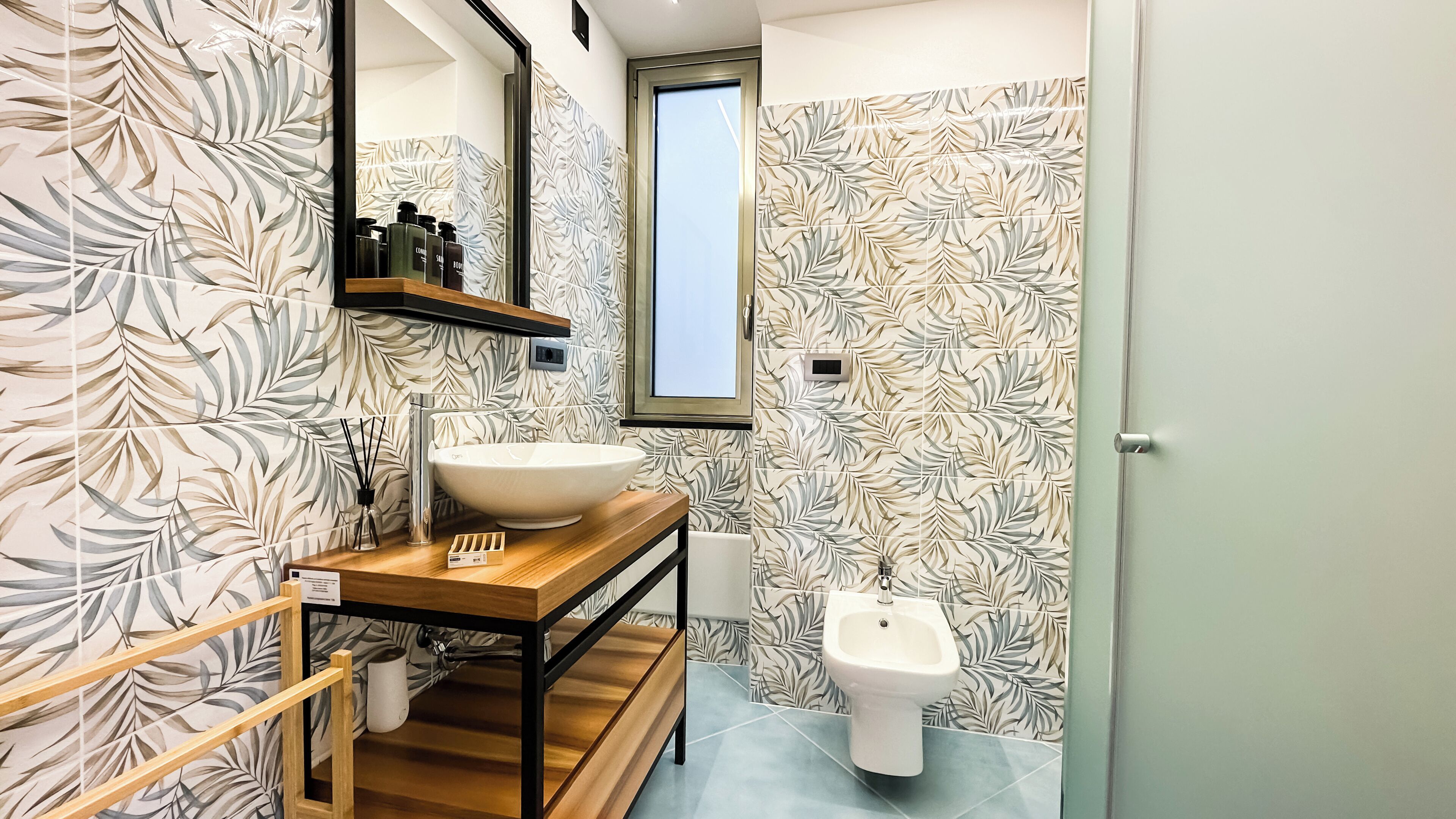 A modern bathroom with a large mirror, a wooden vanity, a white sink, and a bidet.