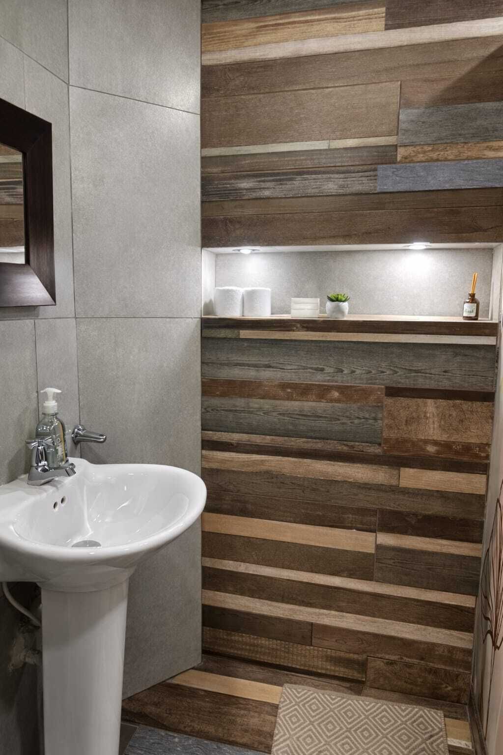 A bathroom with a white sink, a mirror, and a shelf with toiletries.