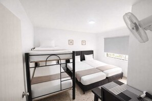 A room with bunk beds, a desk, a chair, a fan, and a window with a view. - Casa Hotel Sweet Home (Medellín)
