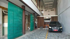 Un área de estacionamiento techada con piso estampado, un automóvil y una escalera que conduce a un nivel superior.