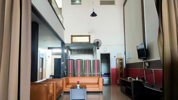 Amplia sala de estar con sofá, mesa de centro y televisor. Se observa un ventilador y una estantería al fondo.