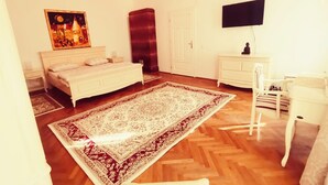 Une chambre à coucher comprenant un lit, un bureau, une chaise, un téléviseur et un grand tapis.