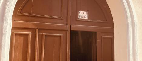 Una gran puerta de madera arqueada con un letrero encima.