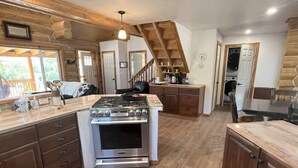 Un'ampia cucina con mobili in legno, un'isola centrale con piano cottura e un'area pranzo con tavolo e sedie.