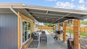 Une terrasse extérieure équipée d’un barbecue, de sièges et d’un espace abrité.