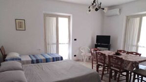 Ein Schlafzimmer mit zwei Betten, einem Esstisch mit Stühlen, einem Fernseher und einem Deckenventilator.