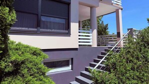 A modern building with a staircase, large windows, and a balcony. - Holiday apartment with outdoor pool and air conditioning (Balatonföldvár)
